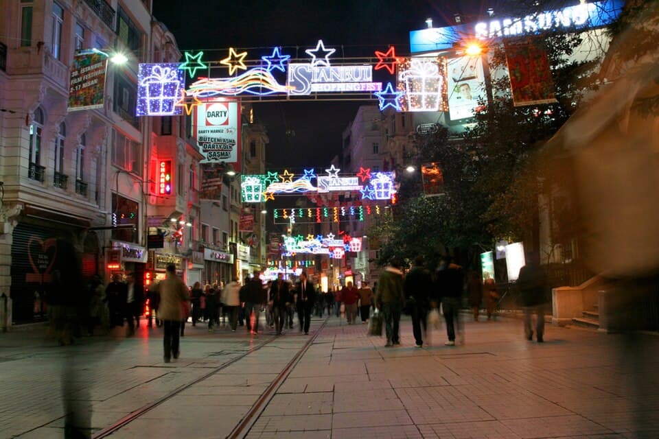 Crowds walking under illuminated signs on Istiklal Street at night